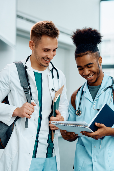 two men in medical clothing looking at a notebook